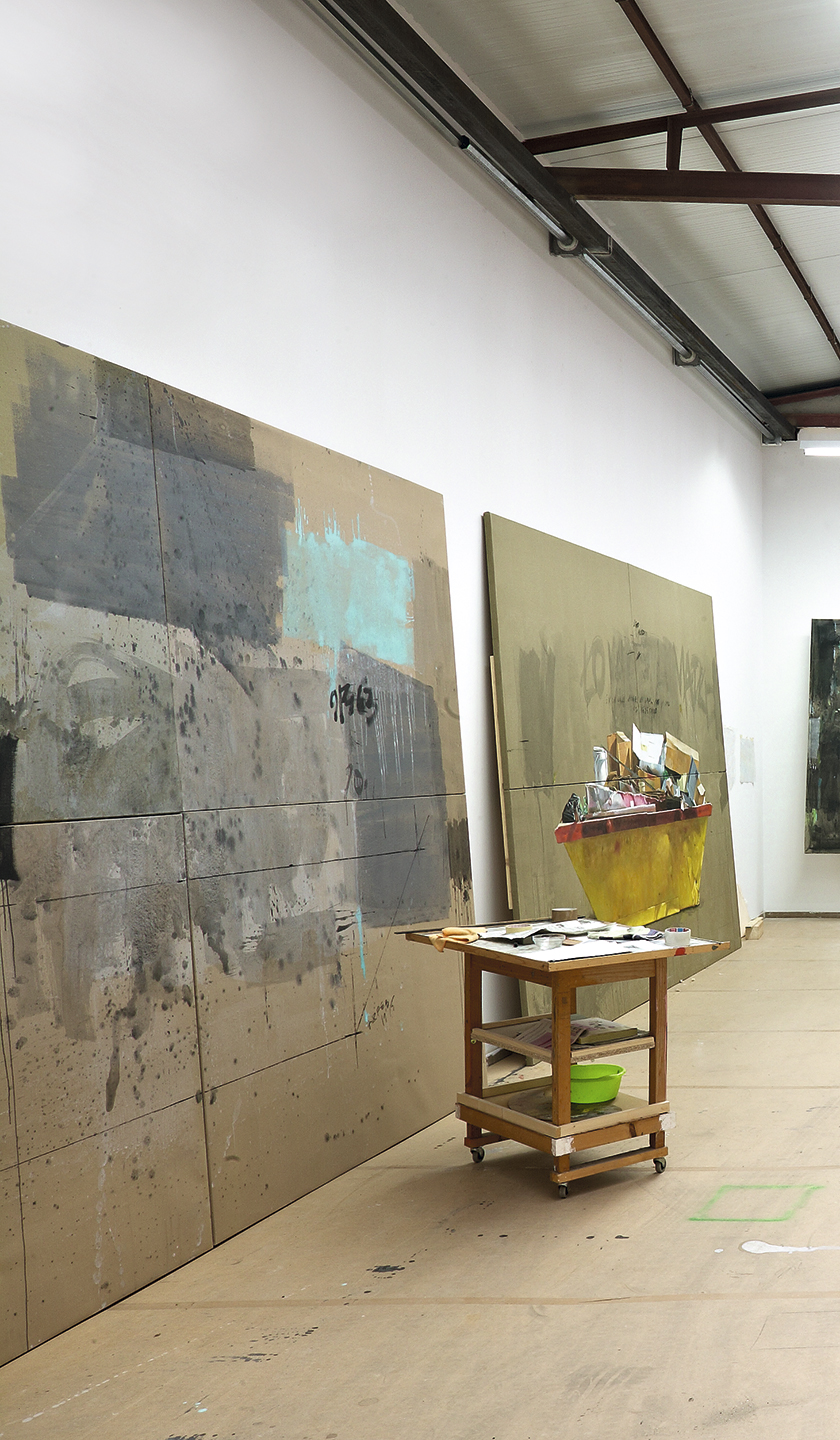 fotografía del estudio del pintor manuel quintana martelo, de dos cuadros grandes apoyados en pared del proyecto urban still life y mesa de trabajo