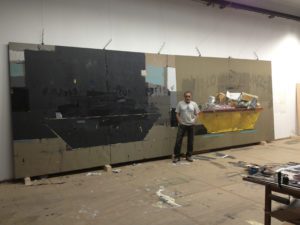 Fotografía del pintor Manuel Quintana Martelo, delante de una obra de grandes dimensiones que forma parte de la serie containers.